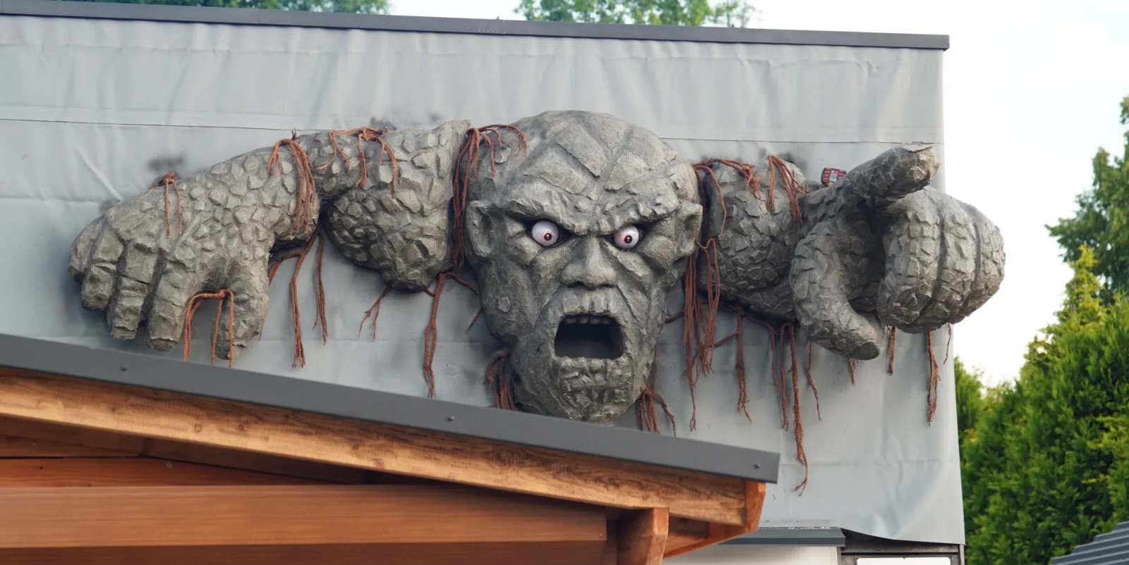 Sculpted stone giant climbing over a roof edge
