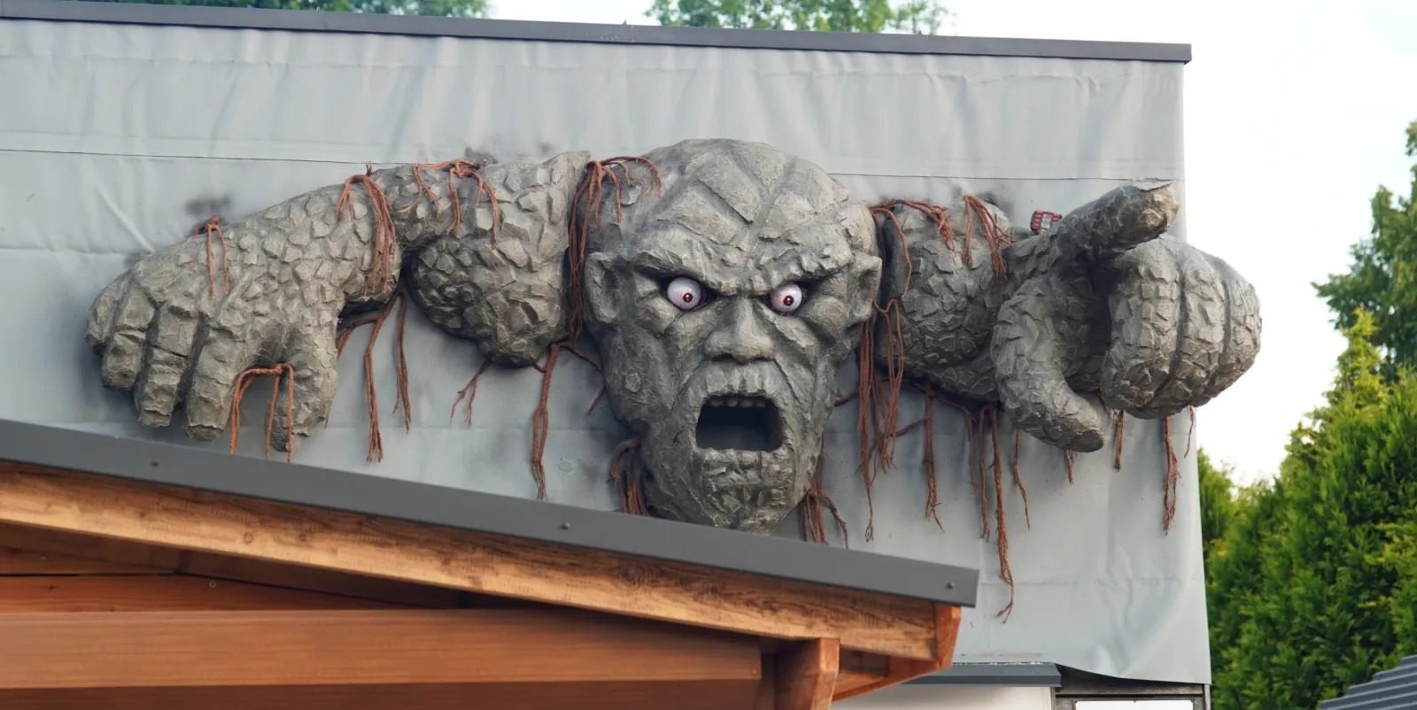 Sculpted stone giant climbing over a roof edge